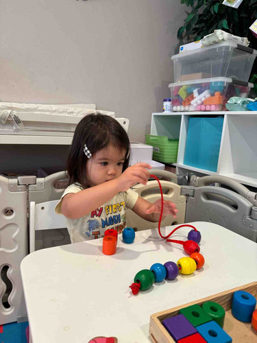 Child threading colourful beads